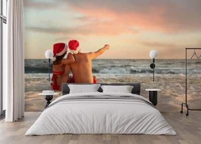 Lovely couple with Santa hats together on beach, back view. Christmas vacation Wall mural