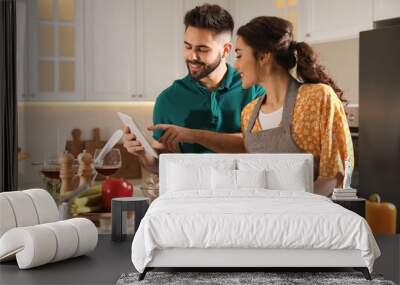 Lovely young couple with tablet cooking together in kitchen Wall mural