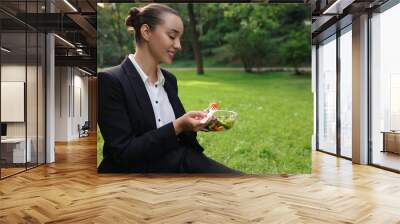 Lunch time. Happy businesswoman with container of salad on green grass in park, space for text Wall mural