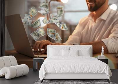 Making money online. Closeup view of man using laptop at table and flying dollars Wall mural