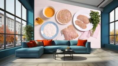 Making schnitzel. Slices of meat with bread crumbs and ingredients on white wooden table, flat lay Wall mural