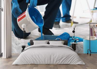 Male decorator pouring paint into tray indoors Wall mural