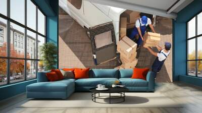 Male movers unloading boxes from van outdoors, above view Wall mural