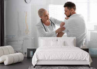 Male orthopedist examining patient's arm in clinic Wall mural