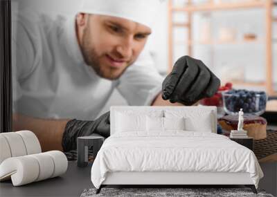 Male pastry chef preparing desserts at table in kitchen Wall mural