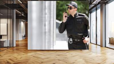 Male security guard using portable radio transmitter outdoors Wall mural