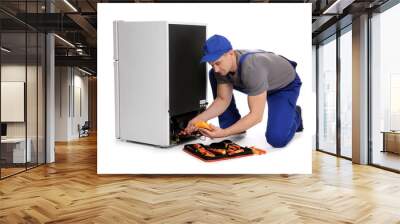 Male technician in uniform repairing refrigerator on white background Wall mural