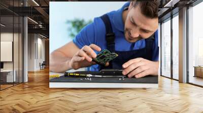 Male technician repairing hard drive at table indoors Wall mural