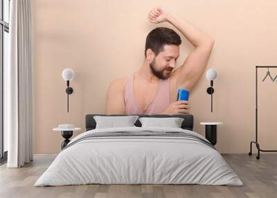 Man applying solid deodorant on beige background Wall mural