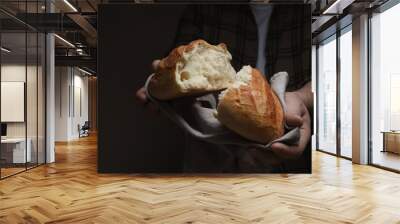 Man breaking loaf of fresh bread on dark background, closeup Wall mural