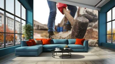 Man breaking stones with sledgehammer outdoors, selective focus Wall mural