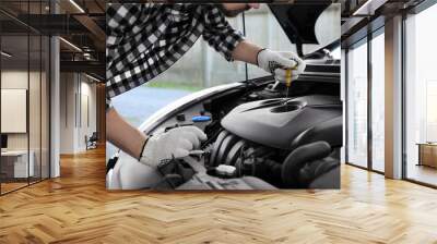 Man checking motor oil level with dipstick in car outdoors, closeup Wall mural