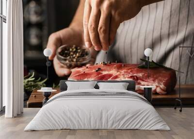 Man cooking fresh raw meat with pepper and rosemary on table, closeup Wall mural