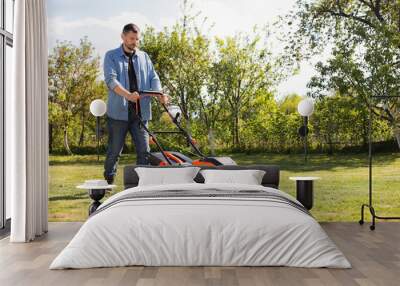 Man cutting green grass with lawn mower in garden Wall mural