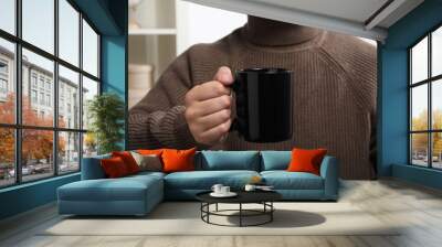 Man holding black mug at home, closeup. Mockup for design Wall mural