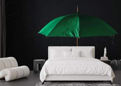 Man holding green umbrella under rain against black background, closeup Wall mural