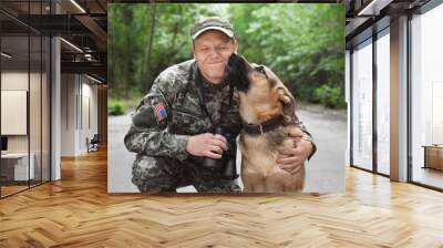 Man in military uniform with German shepherd dog, outdoors Wall mural