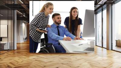 Man in wheelchair with his colleagues at workplace Wall mural