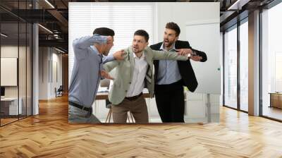 Man interrupting colleagues fight at work in office Wall mural