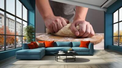 Man kneading dough at table near grey wall, closeup Wall mural