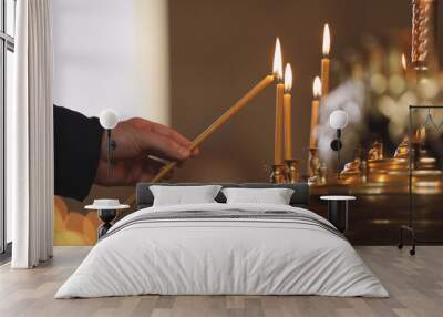 Man lighting candle near stand in church, closeup. Baptism ceremony Wall mural