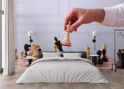 Man moving king chess piece at checkerboard indoors, closeup Wall mural