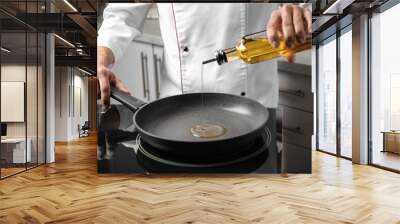 Man pouring cooking oil from bottle into frying pan, closeup Wall mural