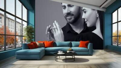 Man putting elegant ring on woman's finger against grey background. Black and white effect Wall mural