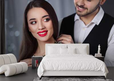 Man putting jewelry on beautiful young woman against blurred lights Wall mural