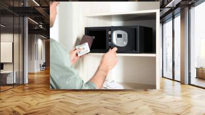 Man putting passport and money into steel safe, closeup Wall mural