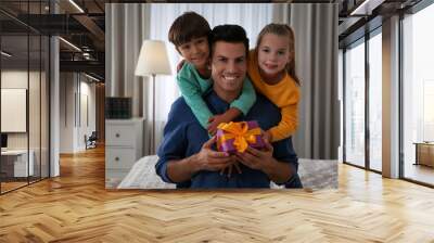 Man receiving gift for Father's Day from his children at home Wall mural