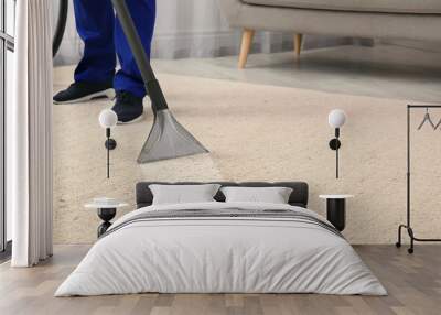 Man removing dirt from carpet with professional vacuum cleaner in room Wall mural