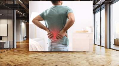 Man suffering from back pain at home. Bad posture problem Wall mural