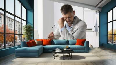 Man suffering from eyestrain at desk in office Wall mural