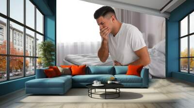 Man suffering from nausea on bed at home. Food poisoning Wall mural