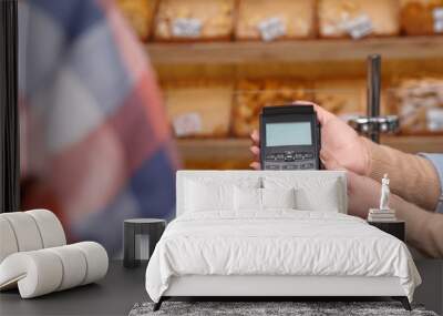 Man using bank terminal for credit card payment in bakery, closeup Wall mural