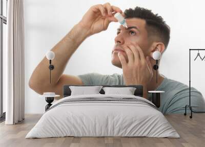 Man using eye drops on white background Wall mural