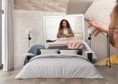 Man using laptop at home for online consultation with psychologist via video chat, focus on screen Wall mural