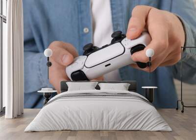 Man using wireless game controller indoors, closeup Wall mural