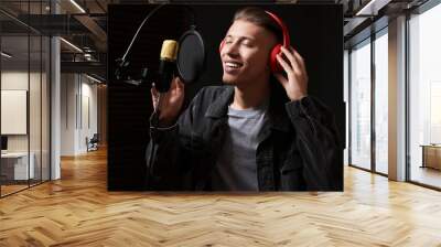 Man wearing headphones singing into microphone in professional record studio Wall mural