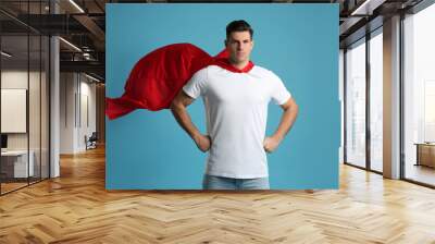 Man wearing superhero cape on light blue background Wall mural