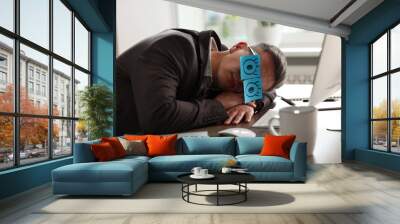 Man with fake eyes painted on sticky notes snoozing at workplace in office Wall mural