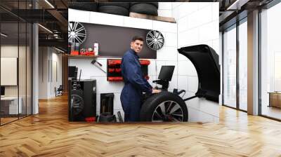 Man working with wheel balancing machine at tire service Wall mural