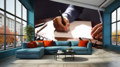 Man writing letter at wooden table indoors, closeup Wall mural