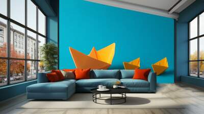 Many handmade orange paper boats on light blue background. Origami art Wall mural