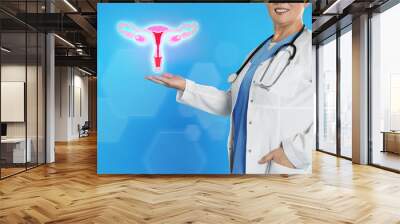 Mature doctor demonstrating virtual icon with illustration of female reproductive system on light blue background, closeup. Gynecological care Wall mural