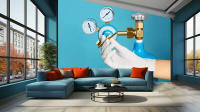 Medical worker checking oxygen tank on light blue background, closeup Wall mural