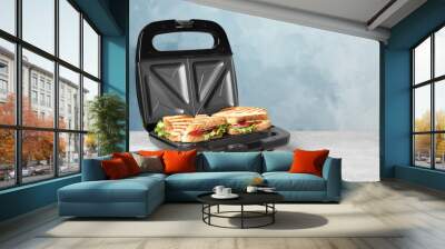 Modern grill maker with sandwiches on grey table near light blue wall, space for text Wall mural