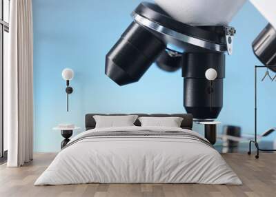 Modern microscope on light blue background, closeup view Wall mural