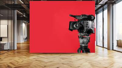 Modern professional video camera on red background. Space for text Wall mural